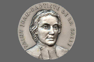 A coin with Saint Jean-Baptiste of La Salle on the face. Links to Gifts That Protect Your Assets